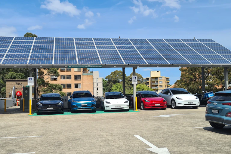 Cars parked under solar panels and alongside charging stations in a car park