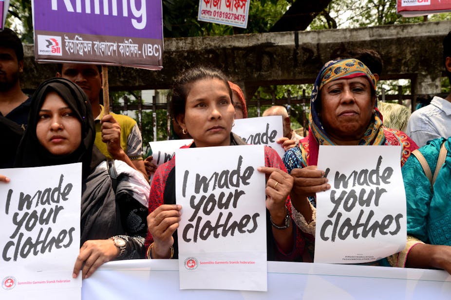 Three women at the front of a protest hold signs saying 'I made your clothes.'