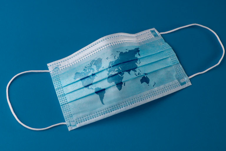 A blue surgical mask with a map of the globe on it