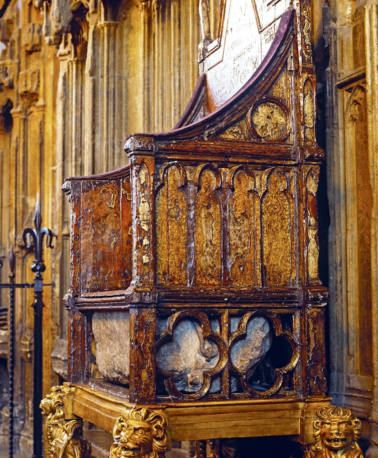 A photo of the coronation chair at Westminster Abbey, where the stone is visible in a chamber built into the chair, directly below the seat.