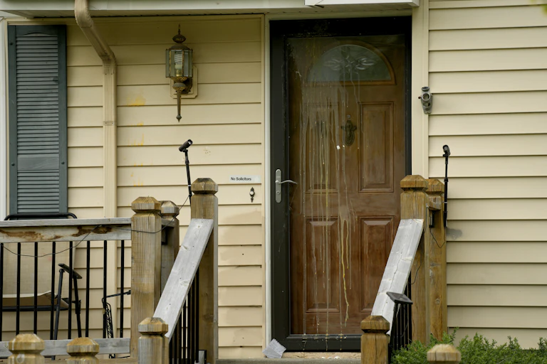 A clapboard-fronted house shows egg stains dripping down the front door.