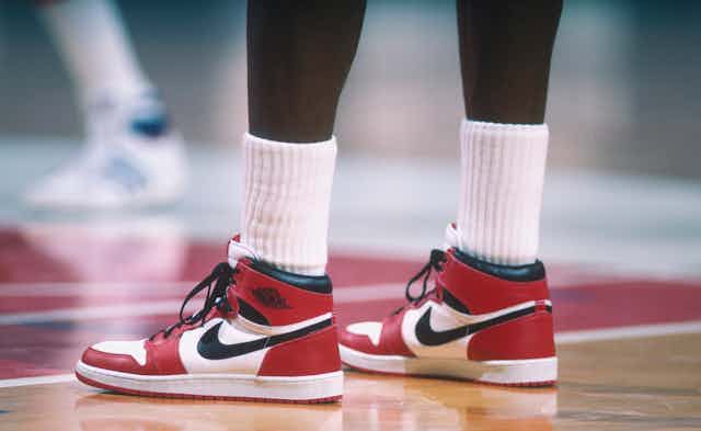 Legs of basketball player wearing red, black and white hightop sneakers.