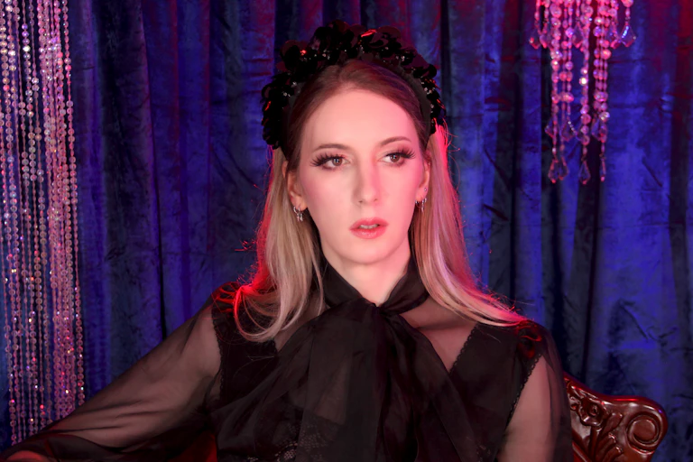 A woman seen in a blouse with black bow and a sparkly headband.