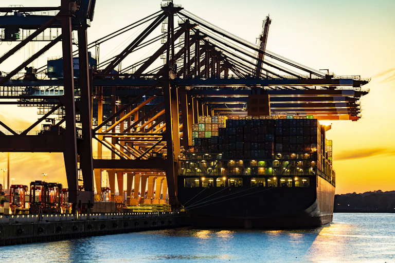 A cargo ship in harbor at daybreak.