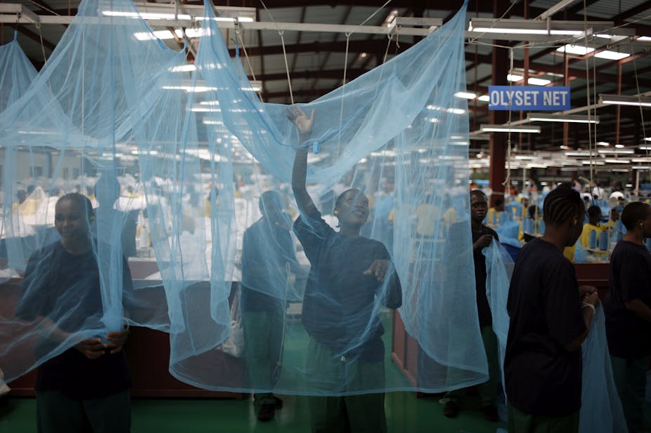 A woman stands inside a mosquito net in a factory setting
