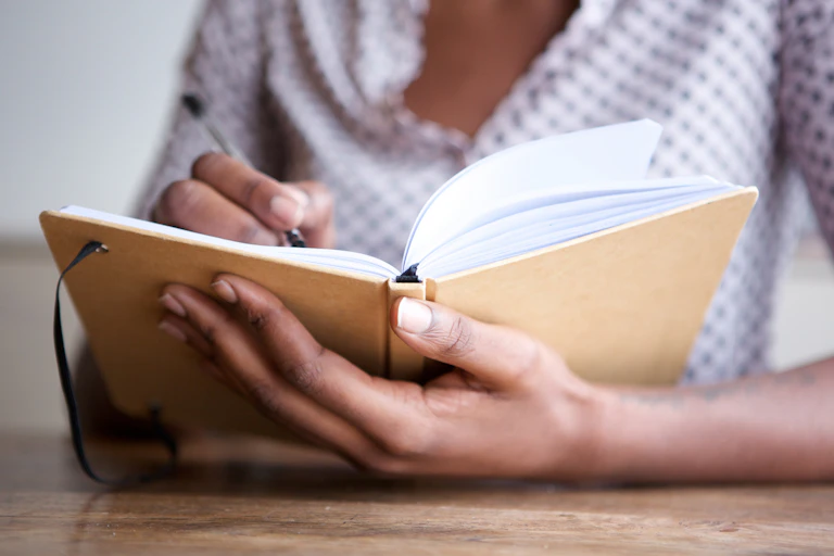Woman's hands writing in notebook