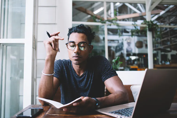 Man with glasses writing in notebook