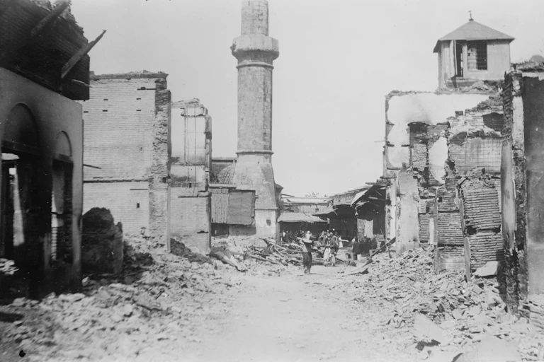 A person walks through a ruined town.