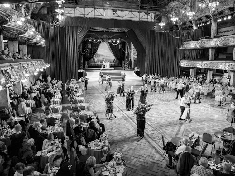 A black and white photo of couples dancing in a ballroom.