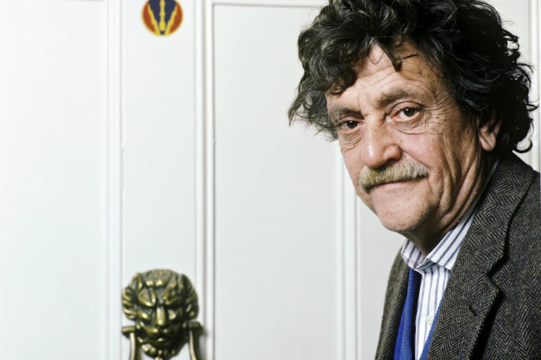 Portrait of older man with mustache and curly hair.