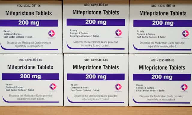 Six boxes of mifepristone tables sitting on a shelf, displaying 200 milligram labels.