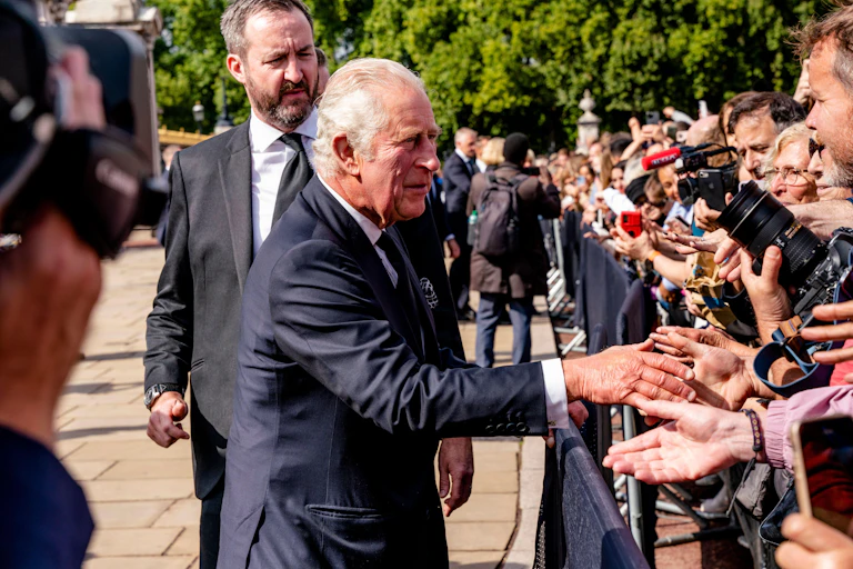 King Charles shaking hands of members of the public across a fence