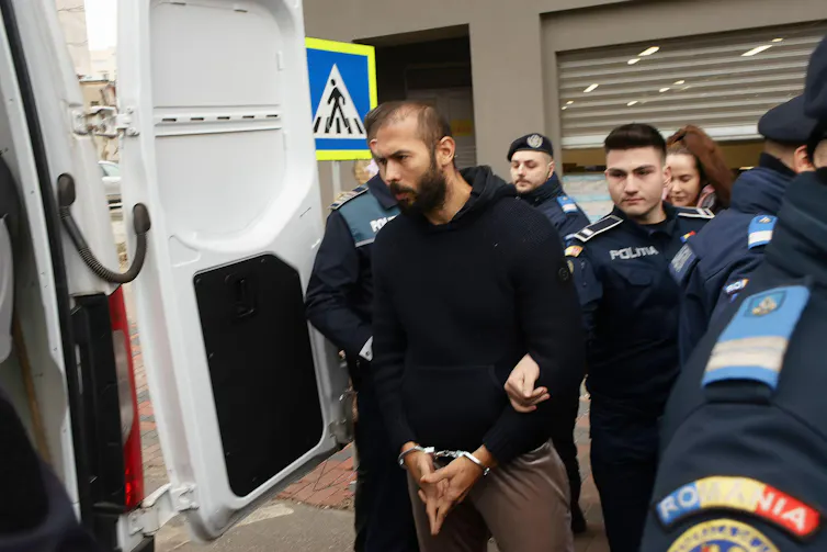 A man in handcuffs with police officers.