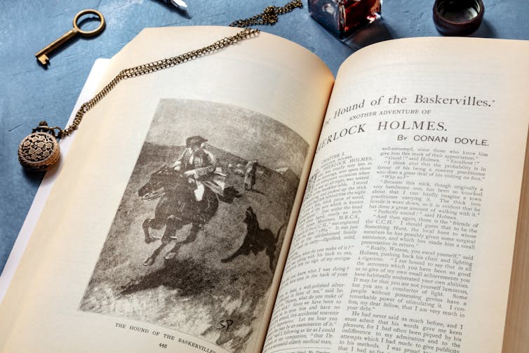 Text of the Hound of the Baskervilles is seen next to a magnifying glass.