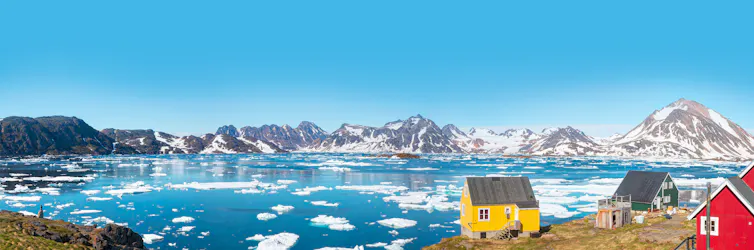 Maisons en bois près d’une grande baie remplie d’icebergs