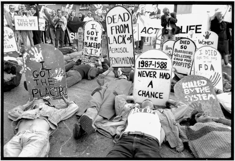 ACT UP protestors lying on the ground with tombstone-shaped signs demanding the FDA allow access to experimental HIV/AIDS drugs