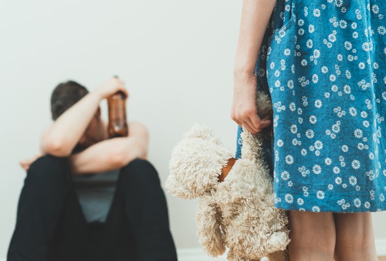 A drunk adult with a child holding a teddy.