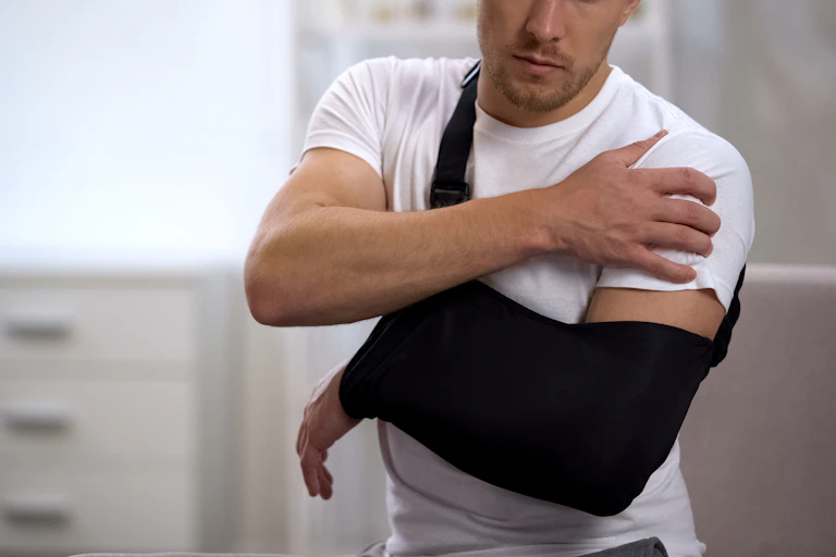 man in sling lifts other arm