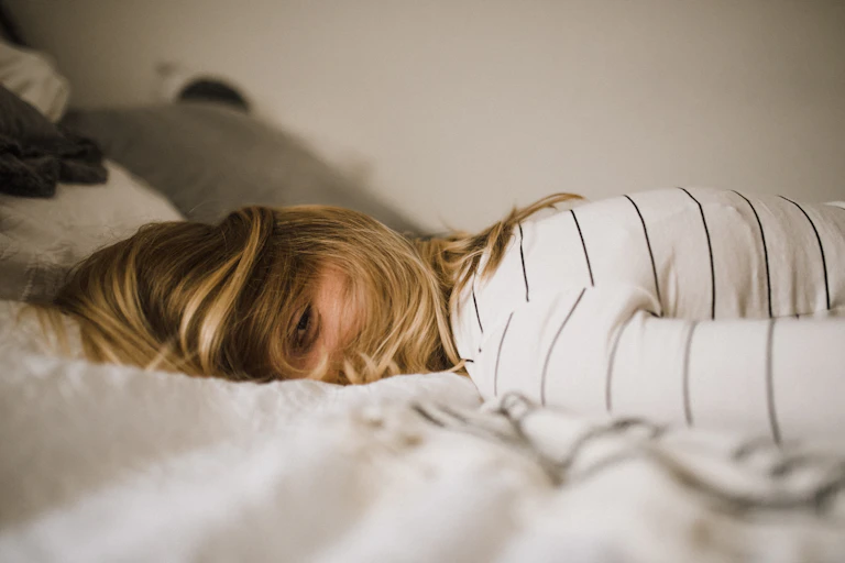 Tired woman lays on bed