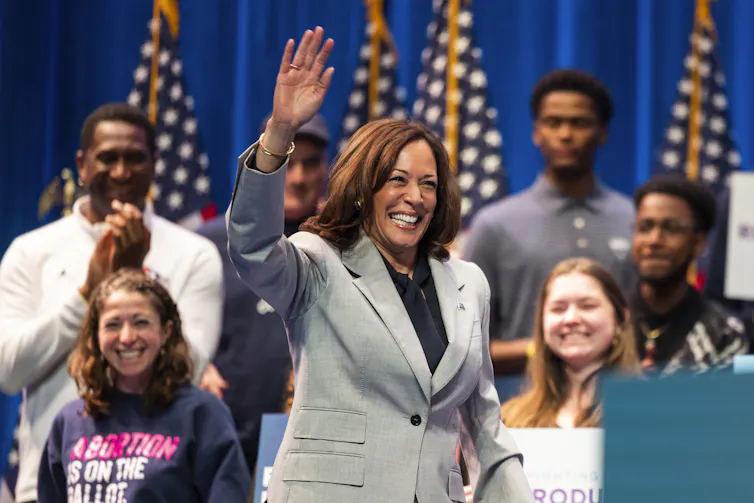 US vice president Kamala Harris waves to a crowd surrounded by staff and supporters.