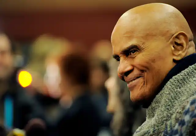 A man wearing a green sweater smiles.