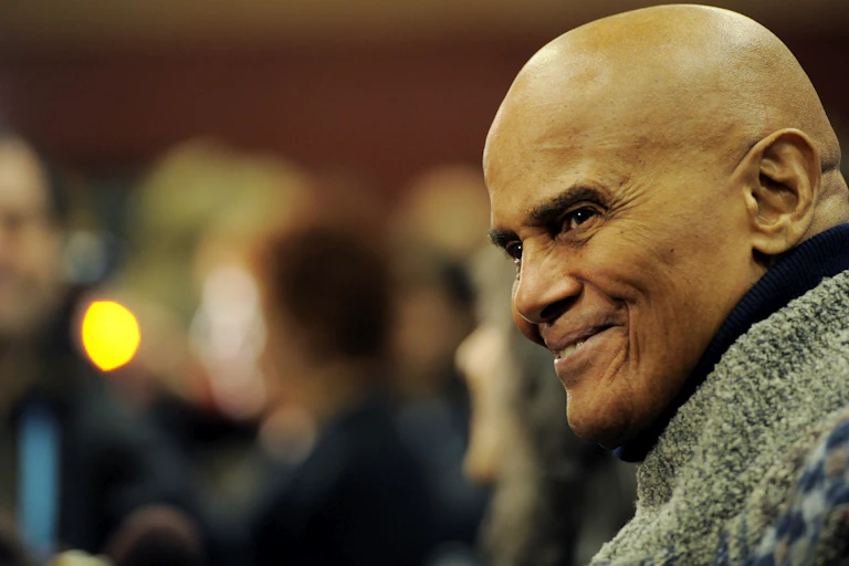 A man wearing a green sweater smiles.