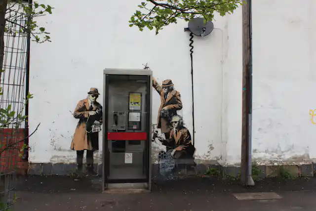 A piece of wall art showing three men in hats as spies next to a telephone booth.