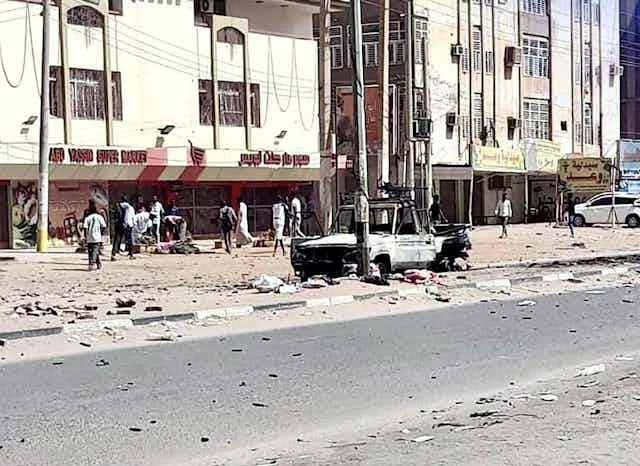 A street in Khartoum, Sudan, with a damaged truck in the foreground.