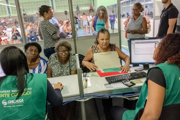 Renégociation de dettes entre débitrices (pour la plupart noires et âgées) et agentes de recouvrement (en vert et de dos). Décembre 2019, foire de renégociation des dettes de Vitoria (Espirito Santo) Brésil.