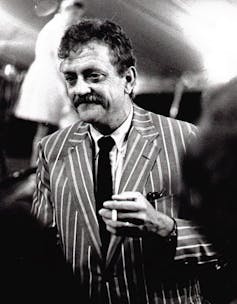 Man in striped suit holding cigarette.