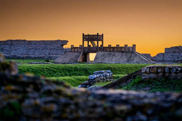 Richborough Roman Fort with the newly reconstructed gateway pictured at sunset.