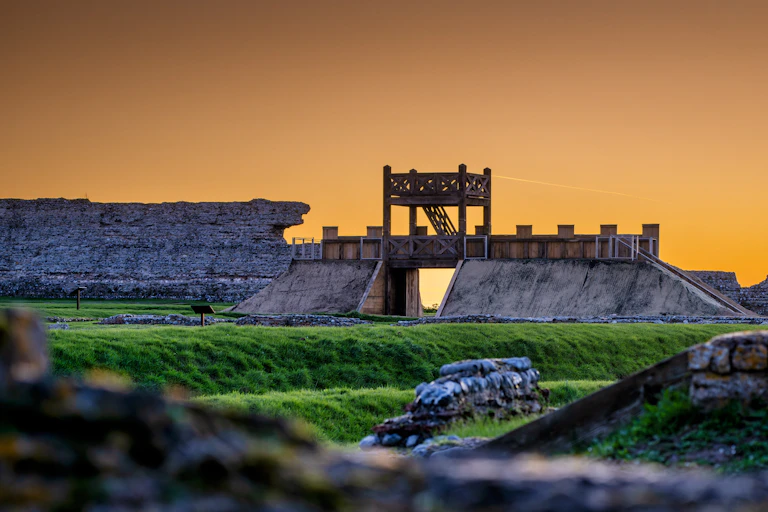 Richborough Roman Fort with the newly reconstructed gateway pictured at sunset.
