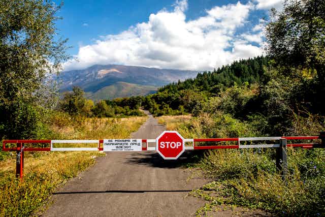 A border sign showing the word stop, with the countryside in the background.