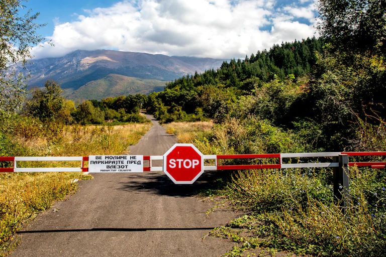 A border sign showing the word stop, with the countryside in the background.