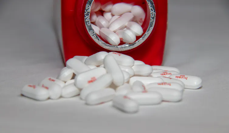 Une bouteille ouverte d’acétaminophène couchée sur le côté avec des caplets qui s’écoulent