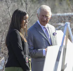 A woman and man seen talking in front of an easel.