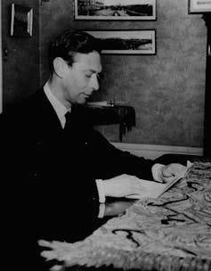 A man seen in a suit at a microphone.