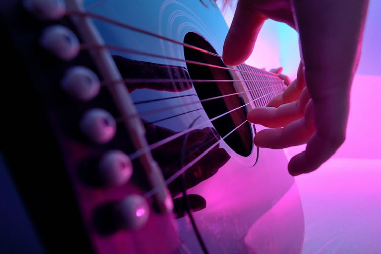 A close up of a hand strumming an acoustic guitar