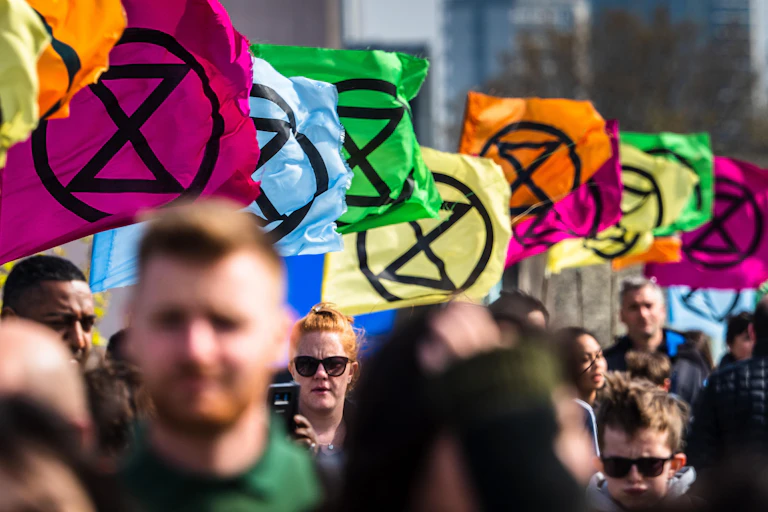 A procession with colourful XR hourglass symbol flags fluttering above.