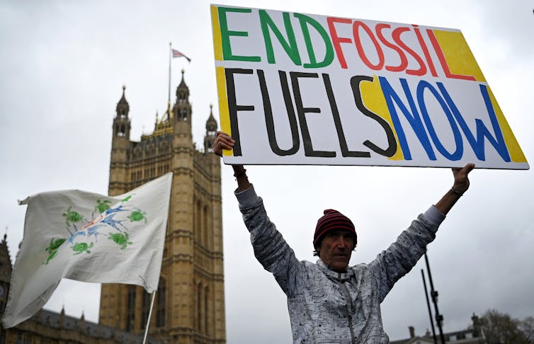 A protester holds up a sign saying 'end fossil fuels now' in London's Parliament Square.