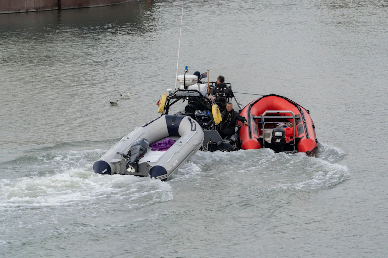 A Border Force boat pulls along two small, empty inflatable boats into a Dover port