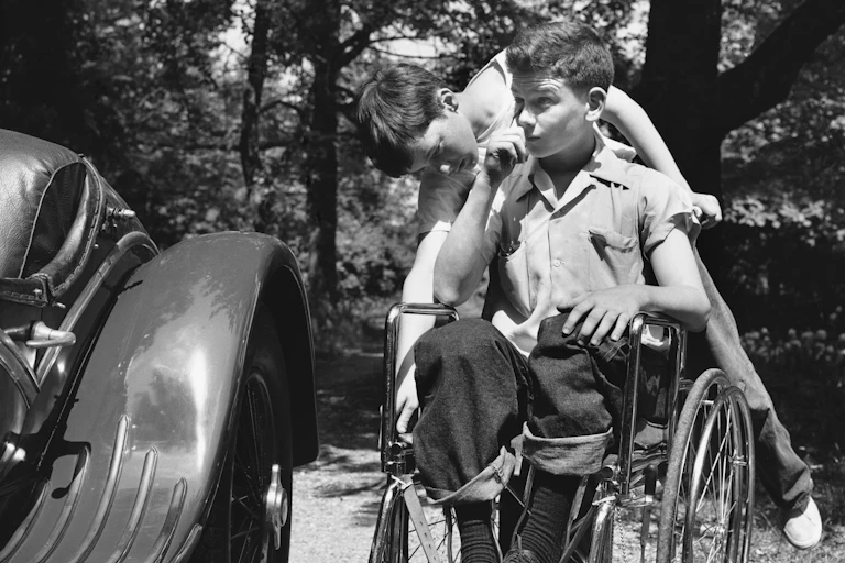 boy pushes another boy in wheelchair
