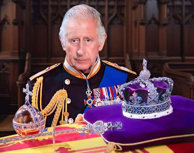King Charles III in military dress, stands behind the imperial state crown, sceptre and orb