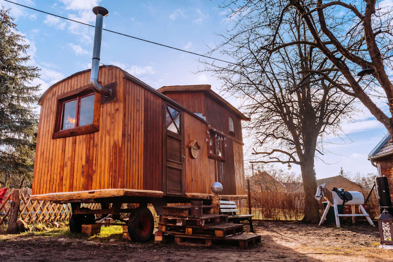 Small wooden tiny home with a metal chimney.
