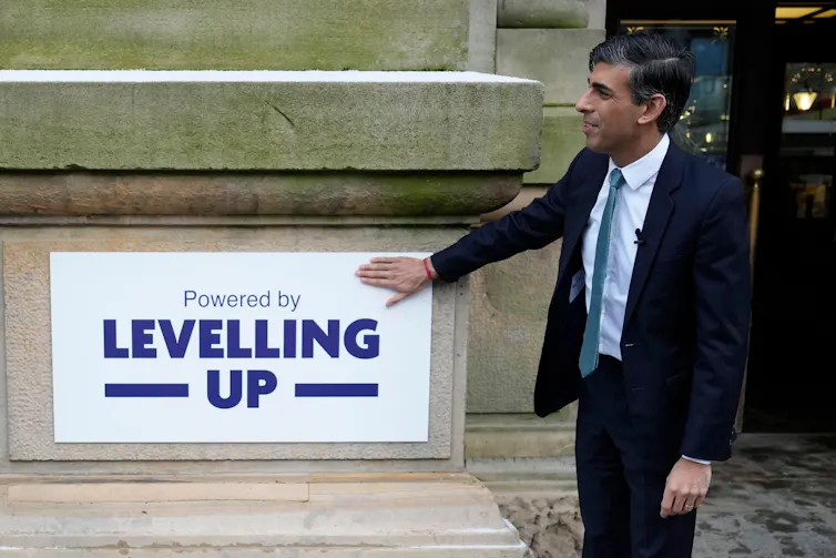 UK PM Rishi Sunak stands in front of a sign that says