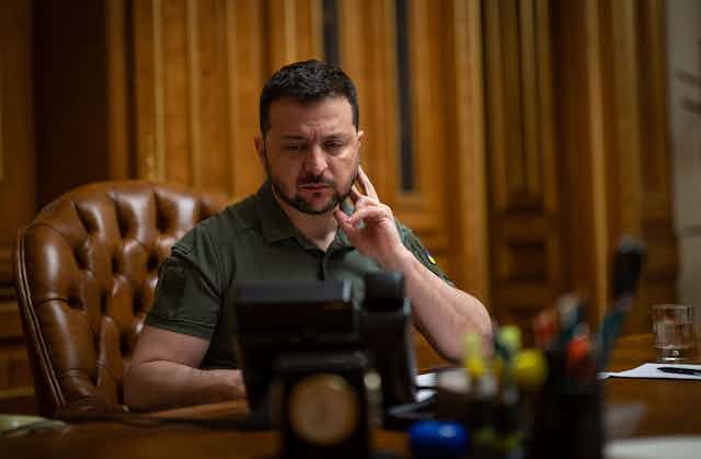 Ukrainian president, Volodymyr Zelensky at his desk on the telephone.