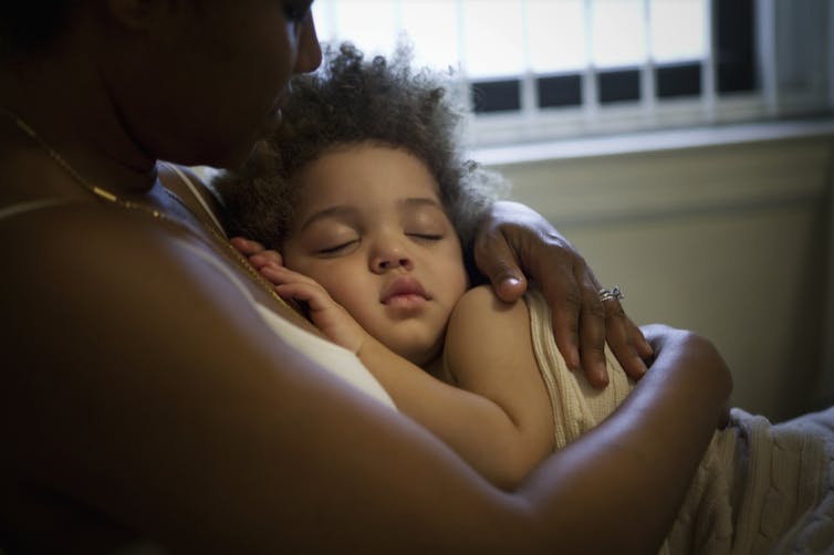 Mother cradling child against chest