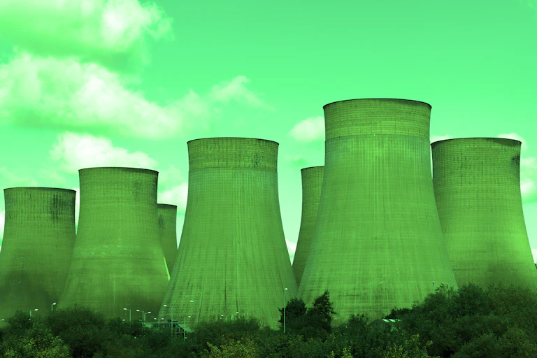 Against a computer-generated green sky, seven green smokestacks sit in an industrial area.