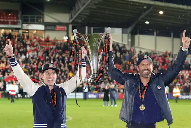Rob McElhenney and Ryan Reynolds holding their trophy.