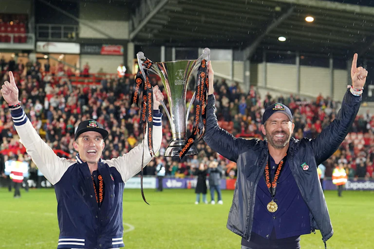 Rob McElhenney and Ryan Reynolds holding their trophy.